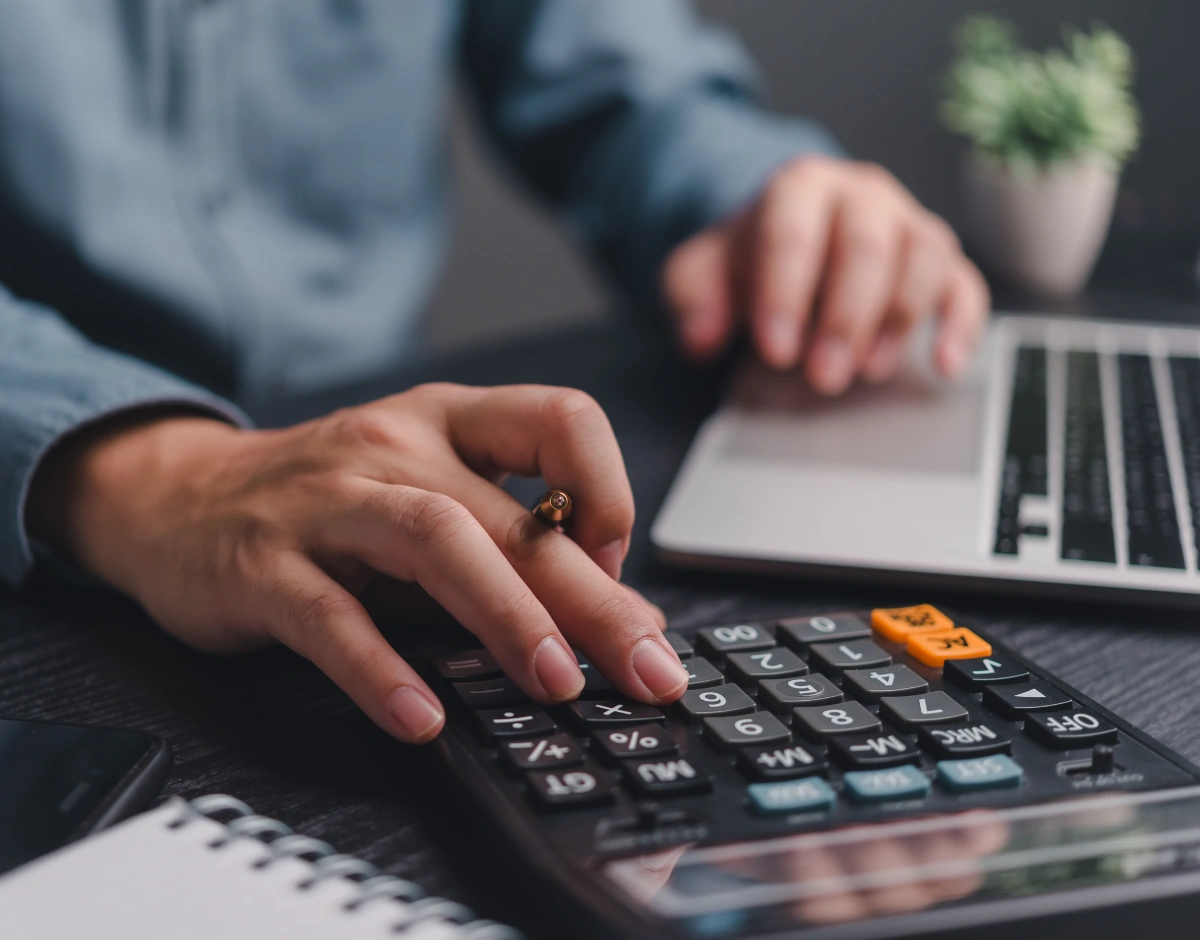 Accountant using a calculator and laptop, representing IT support for accountancy and financial services