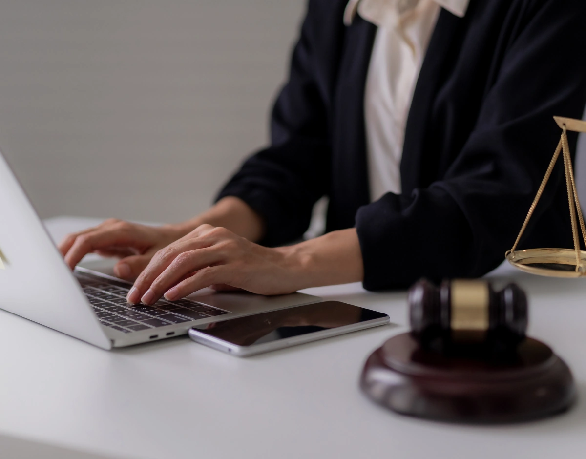 Legal professional working on a laptop beside scales of justice, representing IT support for professional services